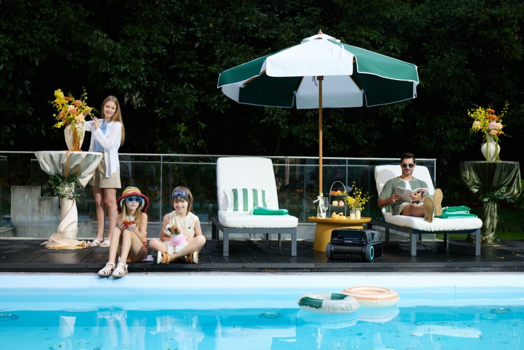 Family relaxing by a swimming pool on a sunny day.