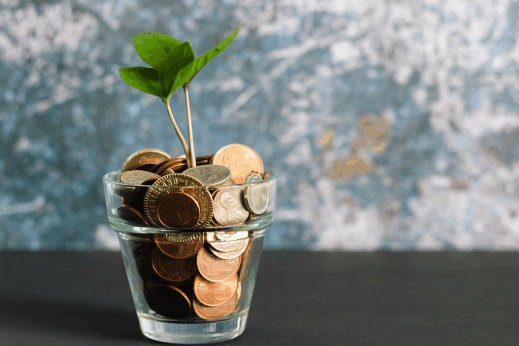 Small plant in a glass jar filled with coins symbolizing ESG investing returns and sustainable growth