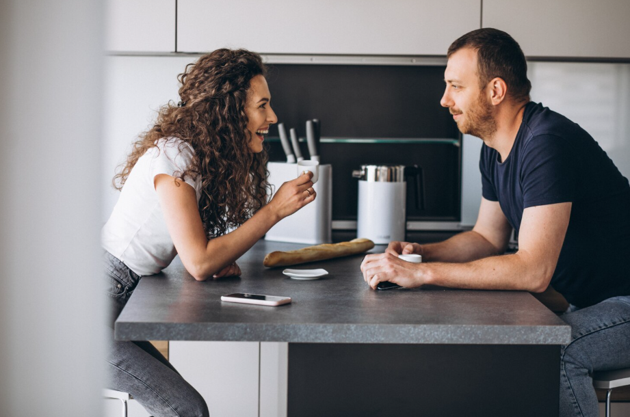Couple enjoying a relaxed, healthy money conversation at the kitchen table