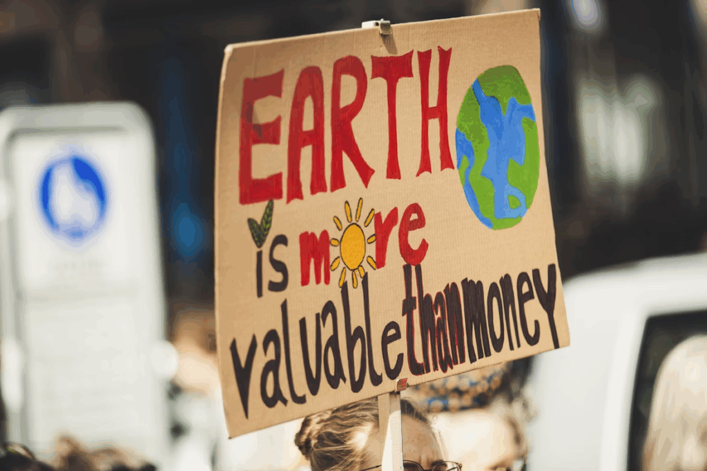 Sign reading “Earth is more valuable than money,” highlighting the link between climate change and money.