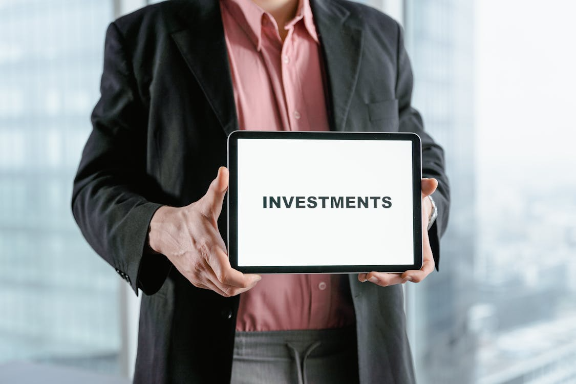 Prrofessional holding a tablet displaying the word investments, representing alternative investments for diversification.